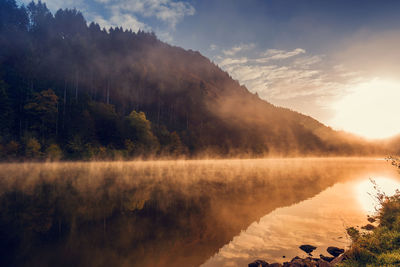 Scenic view of lake by trees against sky