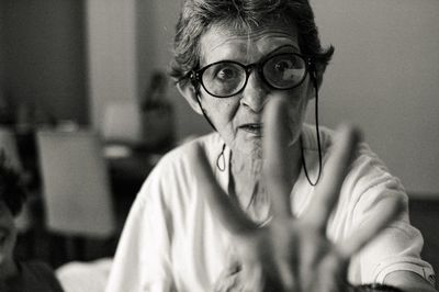 Portrait of woman wearing eyeglasses gesturing while sitting at home