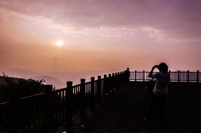 Silhouette people on pier at sunset