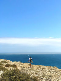 Woman standing by sea against sky