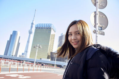 Portrait of smiling young woman against sky