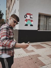 Side view of young man standing against building
