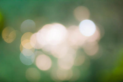 Defocused image of illuminated lights against sky at night