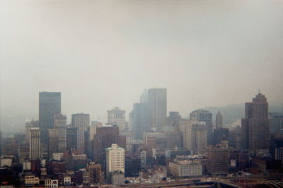 View of cityscape against sky in foggy weather