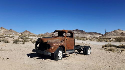 Abandoned car on desert against clear sky