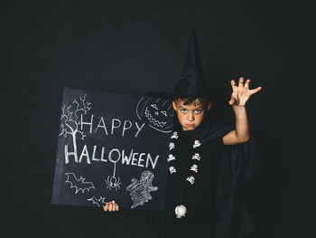 Portrait of boy standing against black background