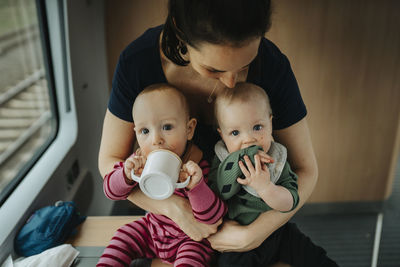 Mother embracing twin babies at home