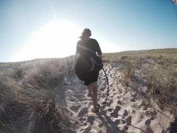 Woman standing on grassy field against sky during sunset