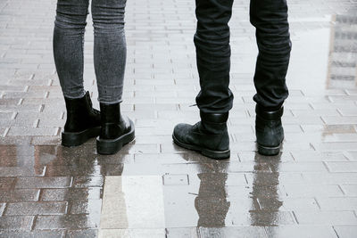 Low section of people standing on wet footpath