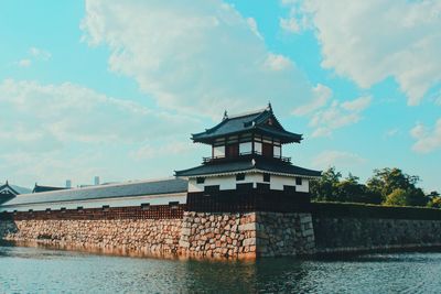 Building by river against cloudy sky