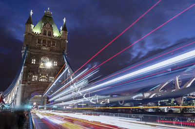 Light trails on bridge against sky at night