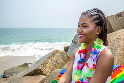 Smiling young woman with colorful artificial flowers at beach