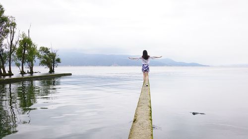 Woman walking on cement structure amidst water
