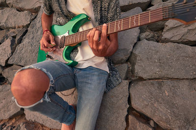 Man playing guitar on rock
