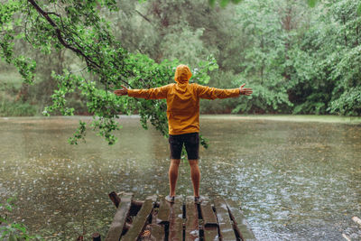 Full length rear view of man standing in front of lake