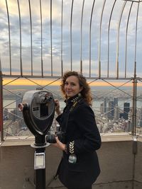 Portrait of young woman standing against view from empire state building, new york