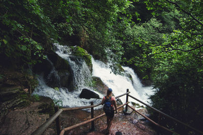 Woman walking on waterfall in forest