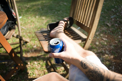High angle view of man holding drink while sitting on chair