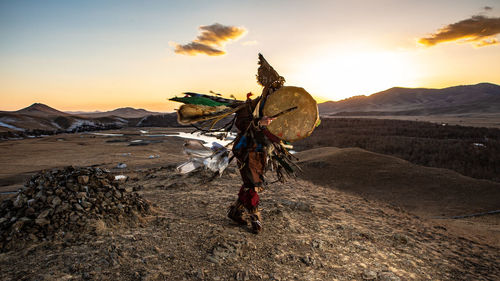 Traditional windmill on field against sky during sunset