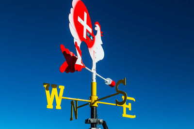 Low angle view of weather vane against blue sky