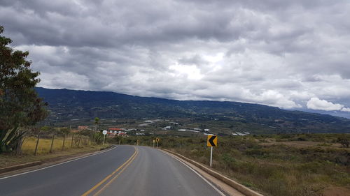 Road by mountains against sky