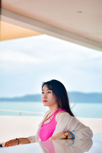 Portrait of young woman standing against sky