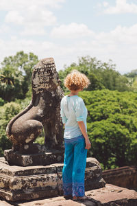 Rear view full length of woman standing by sculpture