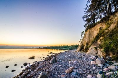 Rocks on beach against sky during sunset