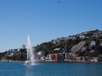 Fountain in city against clear sky