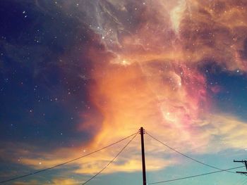 Low angle view of electricity pylon against sky at night