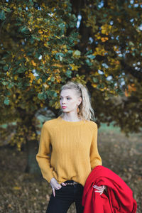 Young woman standing by tree against plants