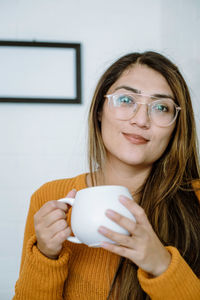 Mexican young woman drinks from a white cup with natural pose