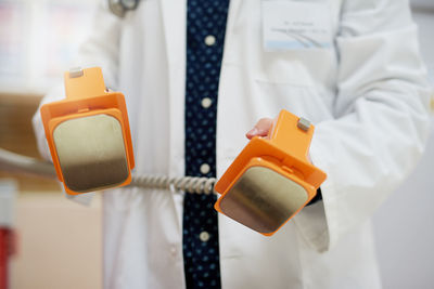 Midsection of female dentist holding dentures while standing in hospital