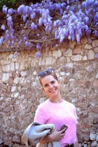 Portrait of smiling woman standing against stone wall