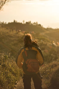 Rear view of woman standing on mountain against sky during sunset