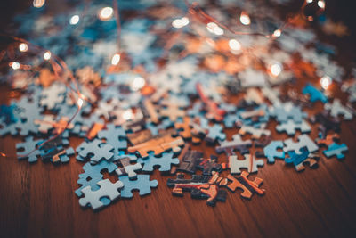 High angle view of illuminated lights and puzzle pieces on table