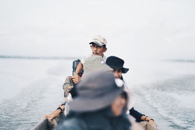 People in sea against sky