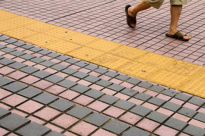 Low section of man walking on cobblestone