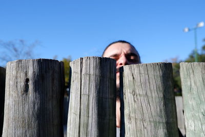 Close-up of wooden posts on fence against sky