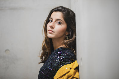 Portrait of beautiful young woman standing against wall