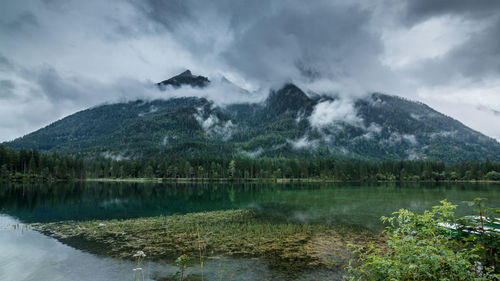 Scenic view of hintersee lake by mountain against cloudy sky