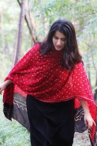 Beautiful young woman with red umbrella standing on land