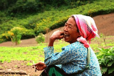 Happy mature female farmer sitting on field