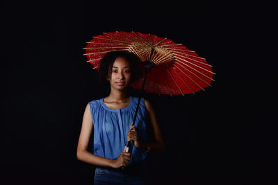 Portrait of woman wearing hat standing against black background