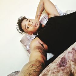 Young tattooed man lying on bed at home