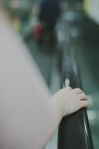 Close-up of woman hand standing on escalator