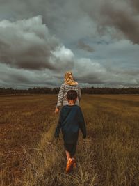 Rear view of woman standing on field against sky