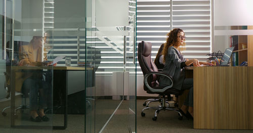 Collegues working in office one woman comparing data from reports and laptop. 