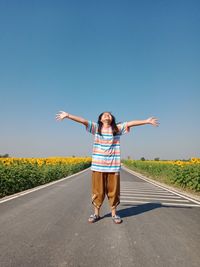 Full length girl with arms outstretched standing on road