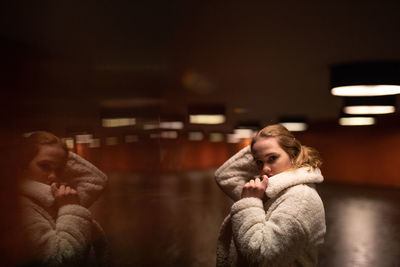 Portrait of young woman in illuminated room